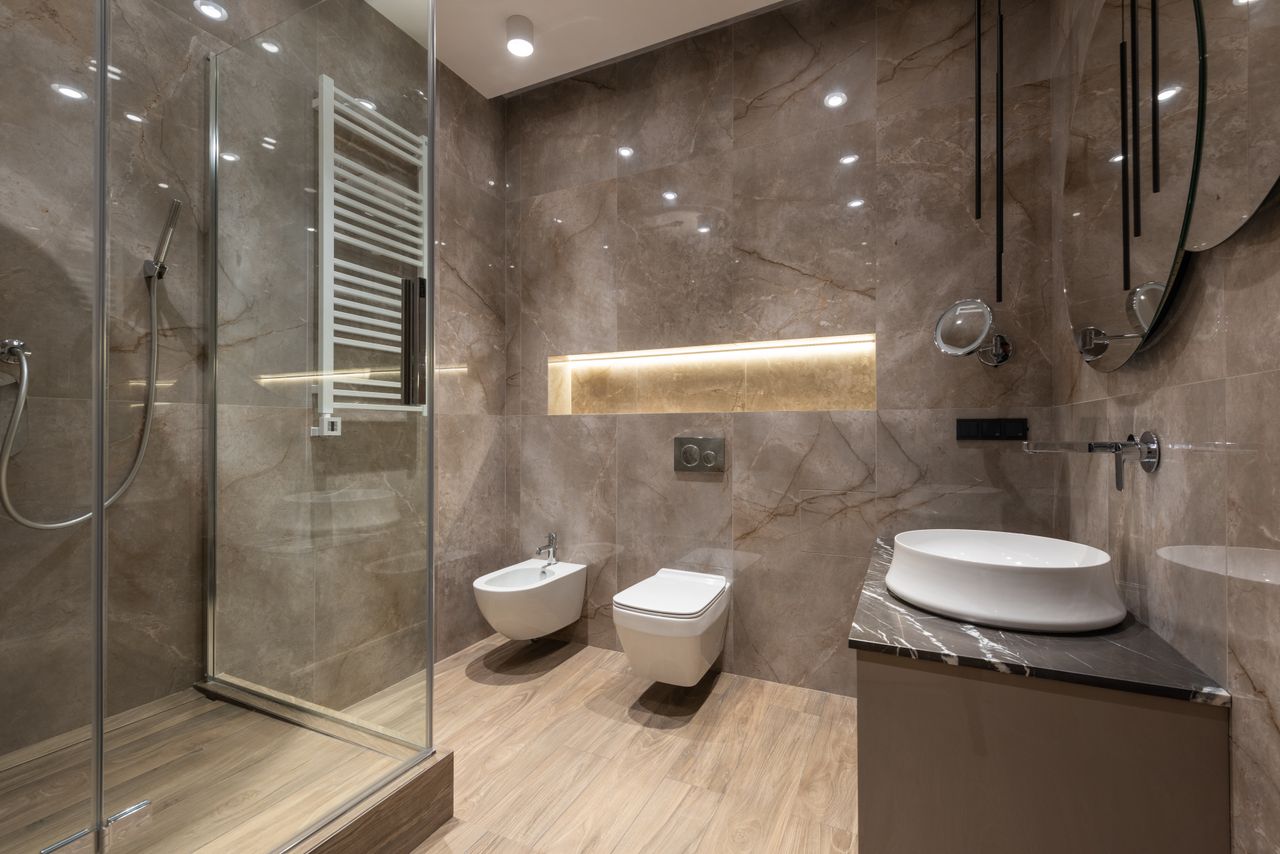 Mastering the First Impression: Your intriguing post title goes here Glass shower cabin and ceramic sink with toilet bowl and bidet in spacious contemporary bathroom with shiny tiles and round mirrors